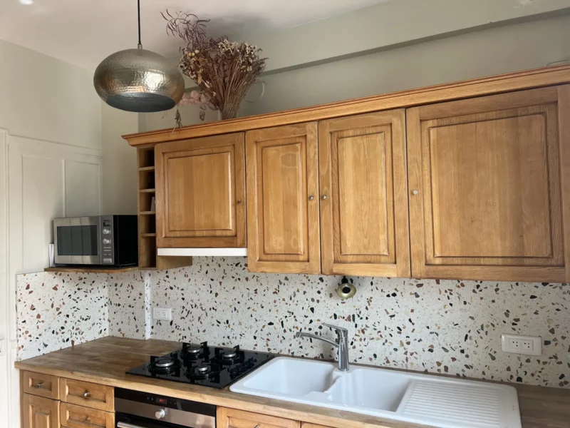 Cuisine rénovée dans un appartement haussmannien à Paris : meubles en bois massif, crédence en terrazzo et suspension martelée