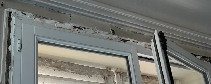 Joint de fenêtre bâclé : silicone grossier et interstices non calfeutrés entre le cadre et le mur