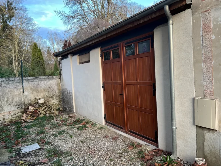 Façade de grange rénovée : enduit ton pierre taloché main et porte double vantail, Seine-et-Marne (77) — TerraRenova
