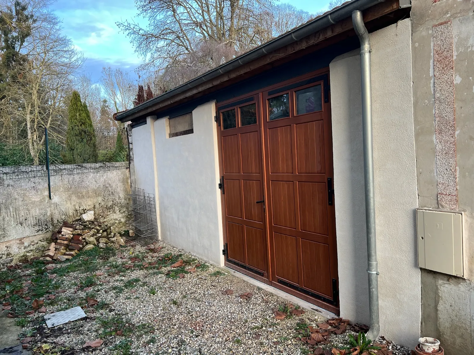 Fa&ccedil;ade de grange r&eacute;nov&eacute;e : enduit ton pierre taloch&eacute; main et porte double vantail, Seine-et-Marne (77) &mdash; TerraRenova